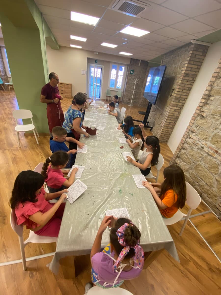 Bambini seduti a un lungo tavolo durante il corso creativo